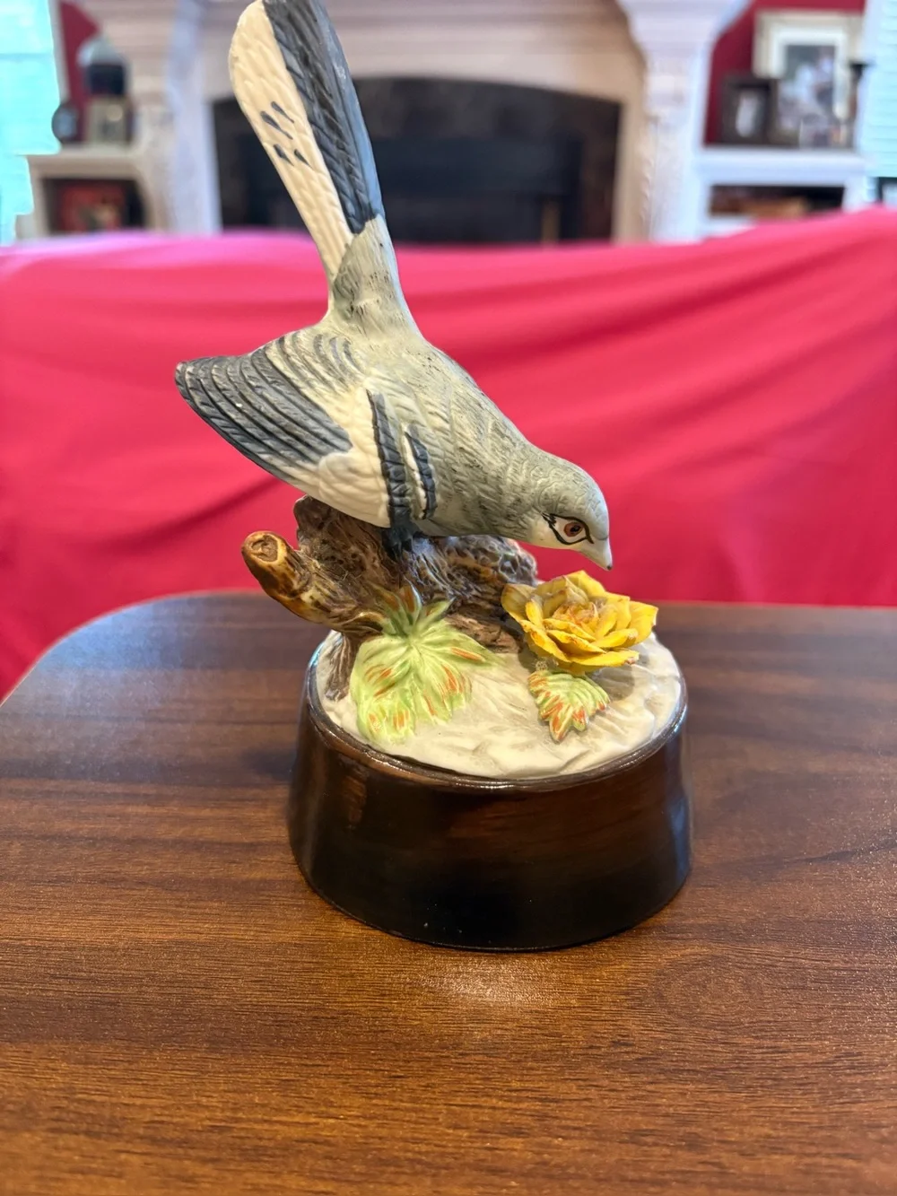 Vintage Grey northern mocking bird perched on a tree stump with yellow flowers.